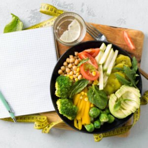 A clean, professional medical flat-lay photograph shot from above. A doctor's notepad, stethoscope, measuring tape, fresh vegetables, nuts, and a lemon arranged neatly on a white background. Soft natural lighting, clinical yet warm aesthetic, no text, no pills, no diet products. High resolution, editorial style.